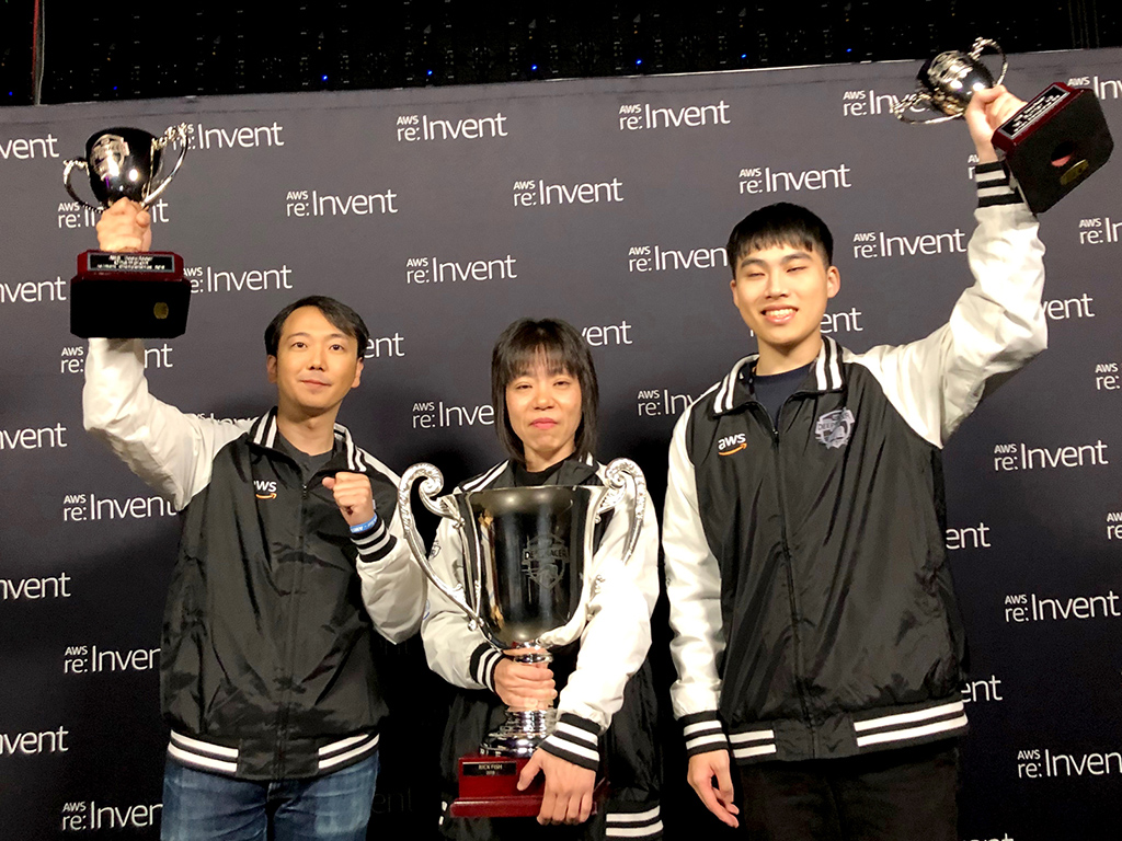 「AWS DeepRacer Championship Cup」の表彰式で3人がカップを手にする様子