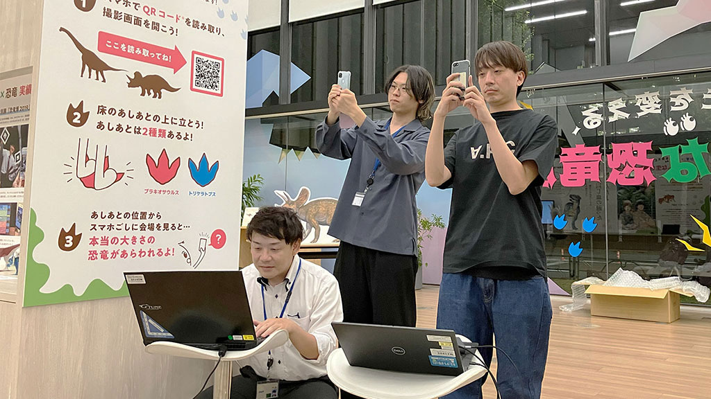 スマートフォンでAR体験を試す宮原豪希さん、荒木涼一さん、田中裕史さん