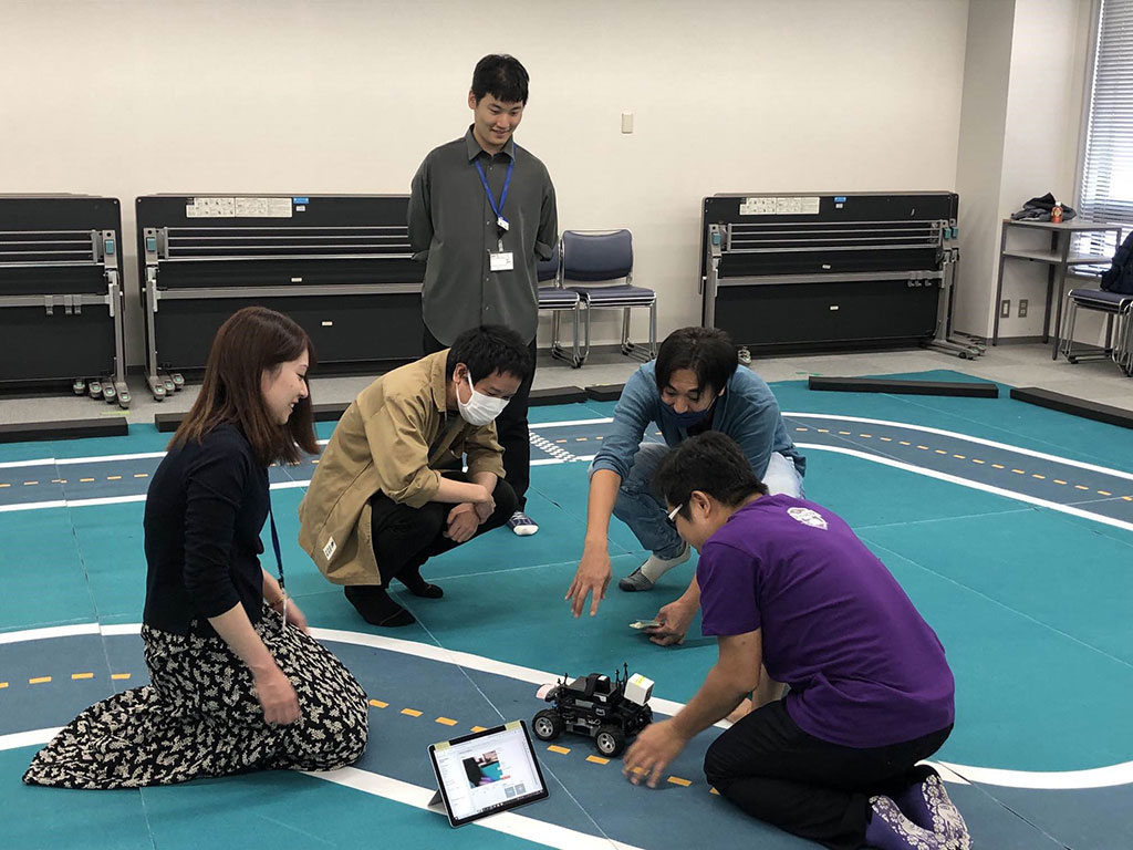 5名の社員が実機を囲み、説明を受けている様子